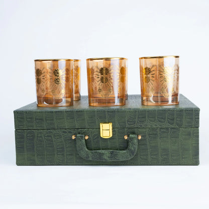 Six gold floral drinking glasses arranged in a premium green presentation storage case