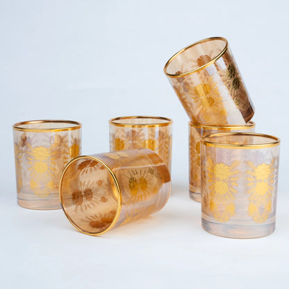 Five amber-tinted glass tumblers with gold floral patterns and gold rims.