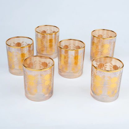 Six clear glass tumblers with gold rims and gold floral patterns.