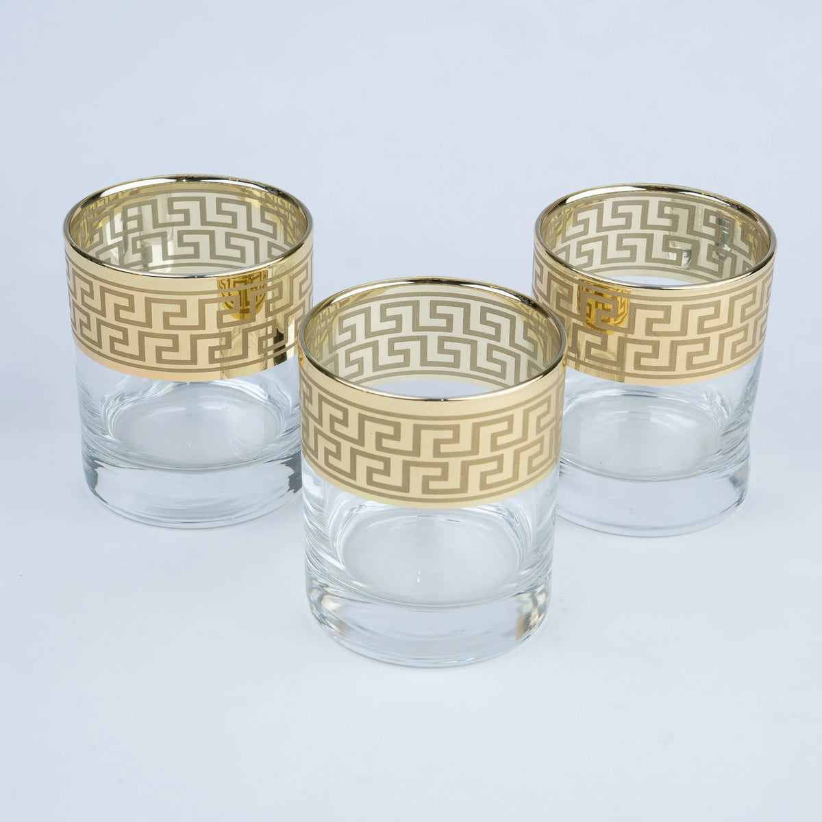 Three clear glass tumblers with gold Greek key pattern bands