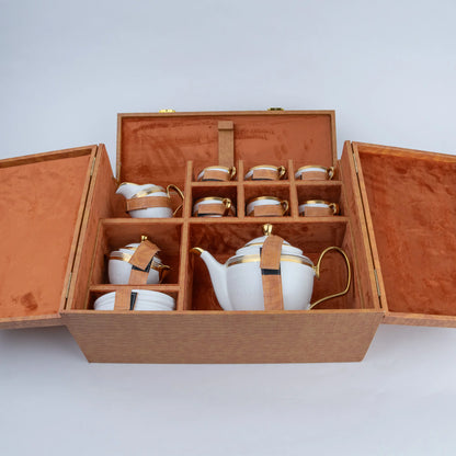 White ceramic tea set with gold accents, six cups and teapot inside textured luxury gift case