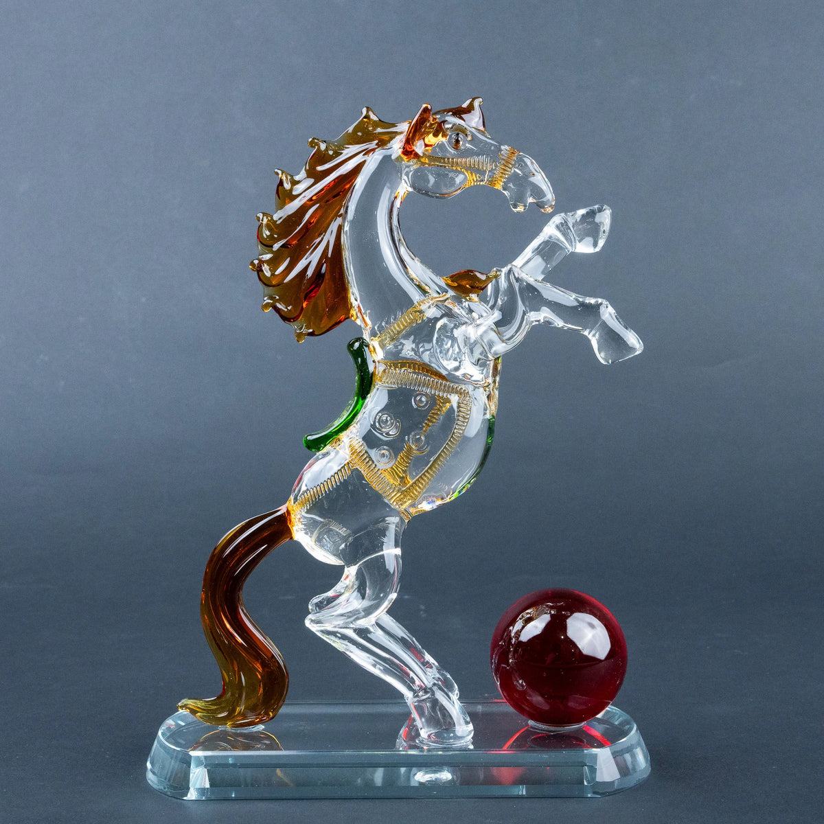 Crystal horse figurine with amber mane, gold details and red sphere on clear base