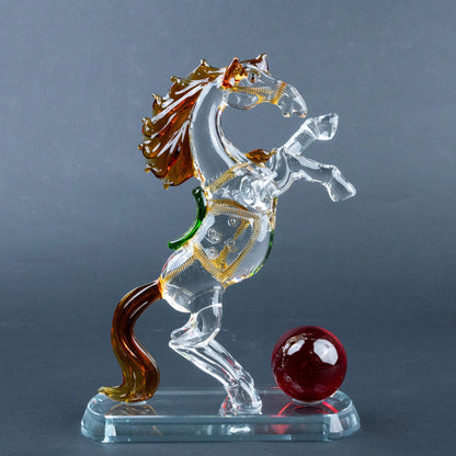 Crystal horse figurine with amber mane, gold details and red sphere on clear base