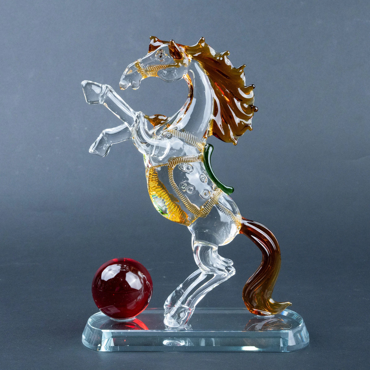 Crystal horse figurine with amber mane, gold details and red sphere on clear base