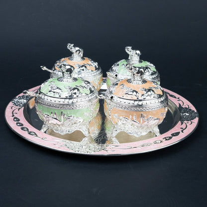 Four elephant lidded decorative containers in mint green and peach arranged on ornate silver tray