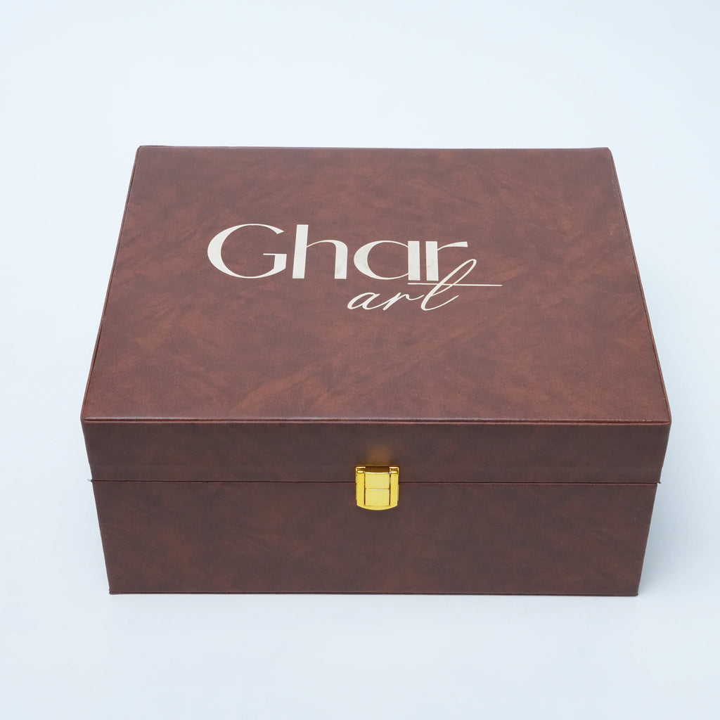 A rectangular brown textured box with a gold clasp and the words 'Ghar art' printed in white on the lid, photographed on a light gray background.