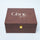 A rectangular brown textured box with a gold clasp and the words 'Ghar art' printed in white on the lid, photographed on a light gray background.