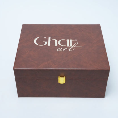 A rectangular brown textured box with a gold clasp and the words 'Ghar art' printed in white on the lid, photographed on a light gray background.