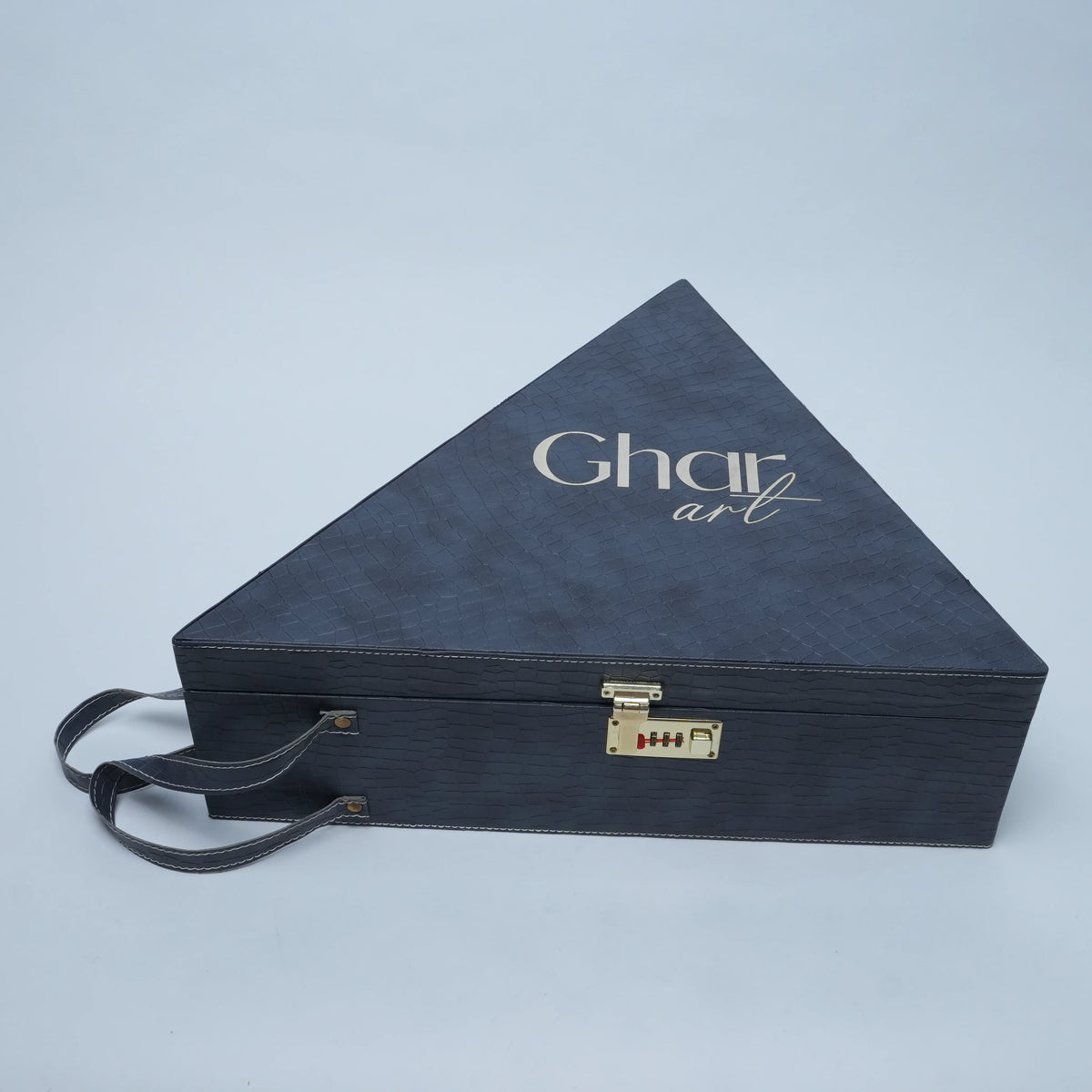 A dark navy blue triangular presentation box with a textured finish, featuring the brand name 'Ghar art' in white script on the top surface. The box has a small gold-toned combination lock on the front and a matching dark handle