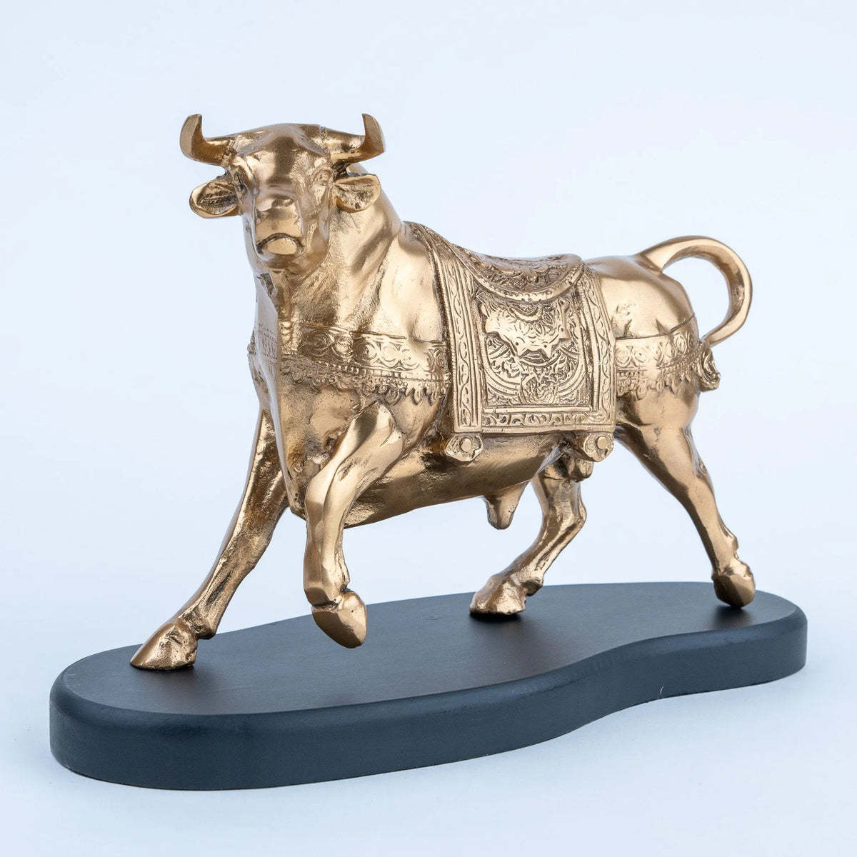 Golden decorative bull statue with patterned covering and black base