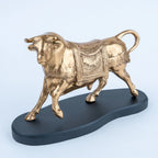 Gold bull figurine with ornate body detailing and elongated black base
