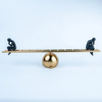 Black human figurines in thoughtful poses on a gold-tone tabletop sculpture.