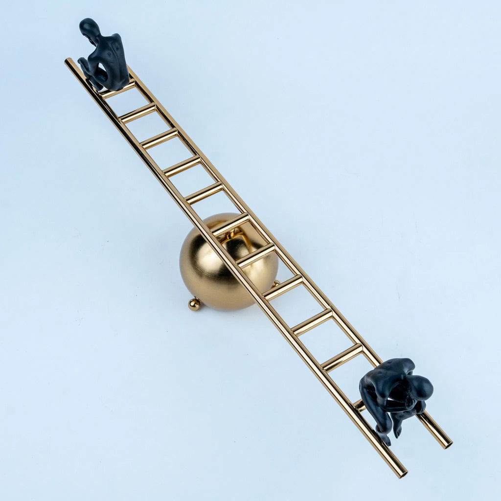 Overhead view of a gold geometric sculpture with two black seated figures