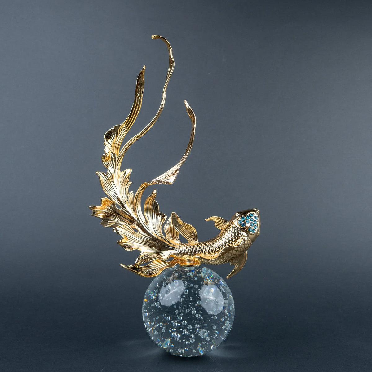 Gold koi fish decorative sculpture with blue crystal-like accents and clear spherical base.