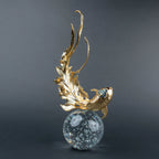 Gold koi fish decorative sculpture with blue crystal-like accents and clear spherical base.