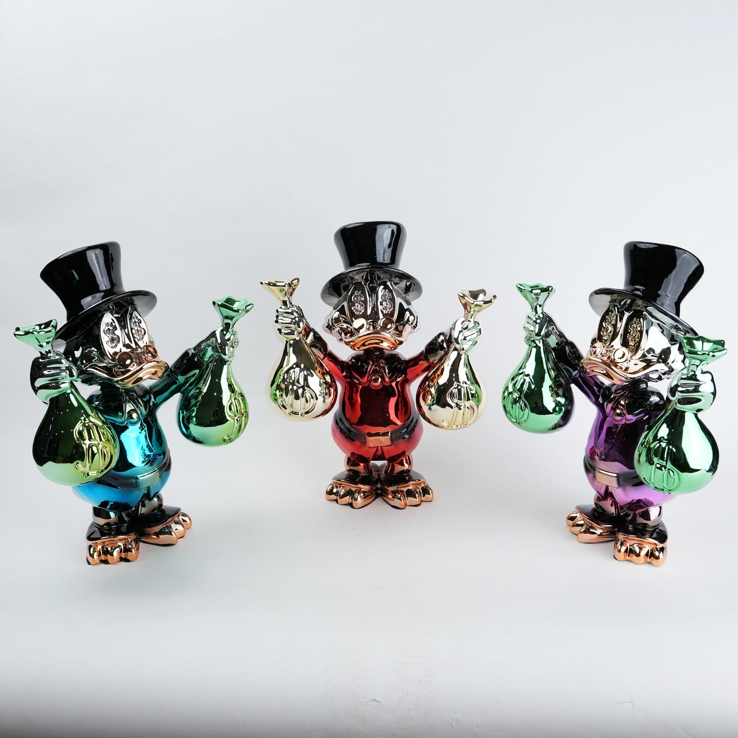 Three colorful glass figurines with top hats and bags on a white background