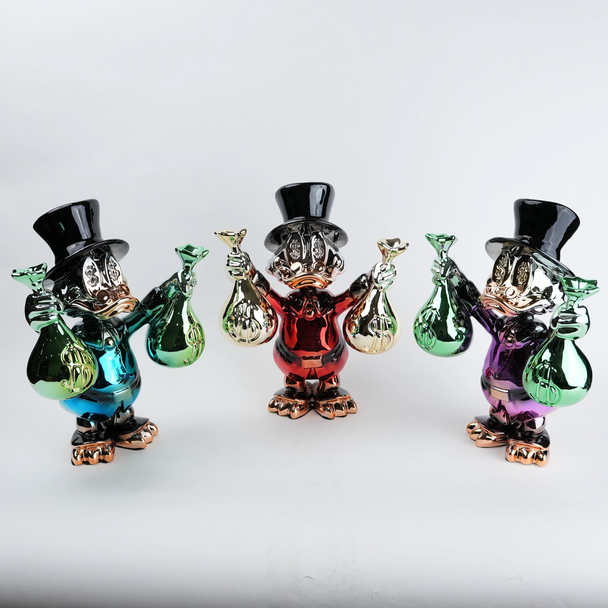 Three colorful glass figurines with top hats and bags on a white background