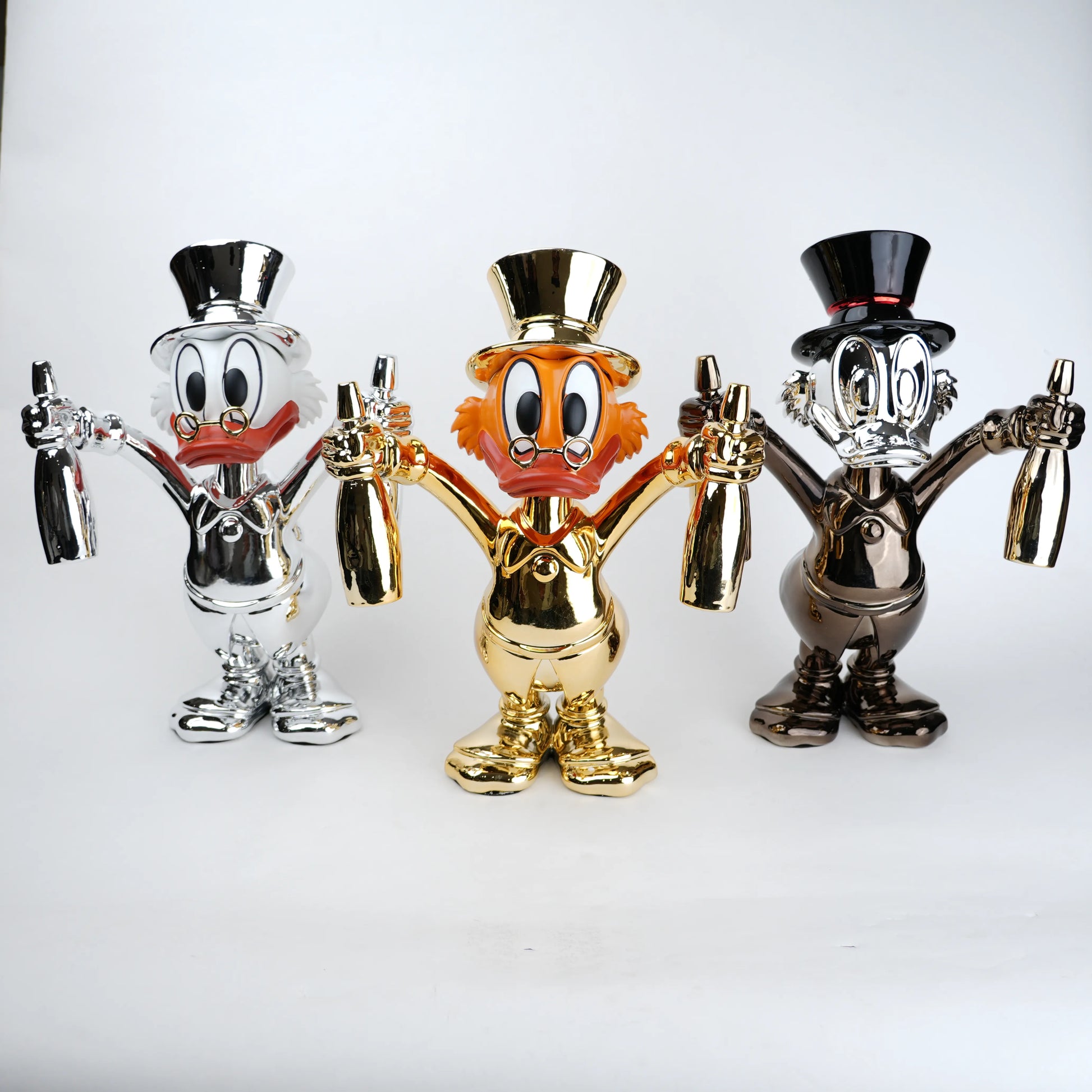 Three metallic figurines of a cartoon character with top hats on a white background