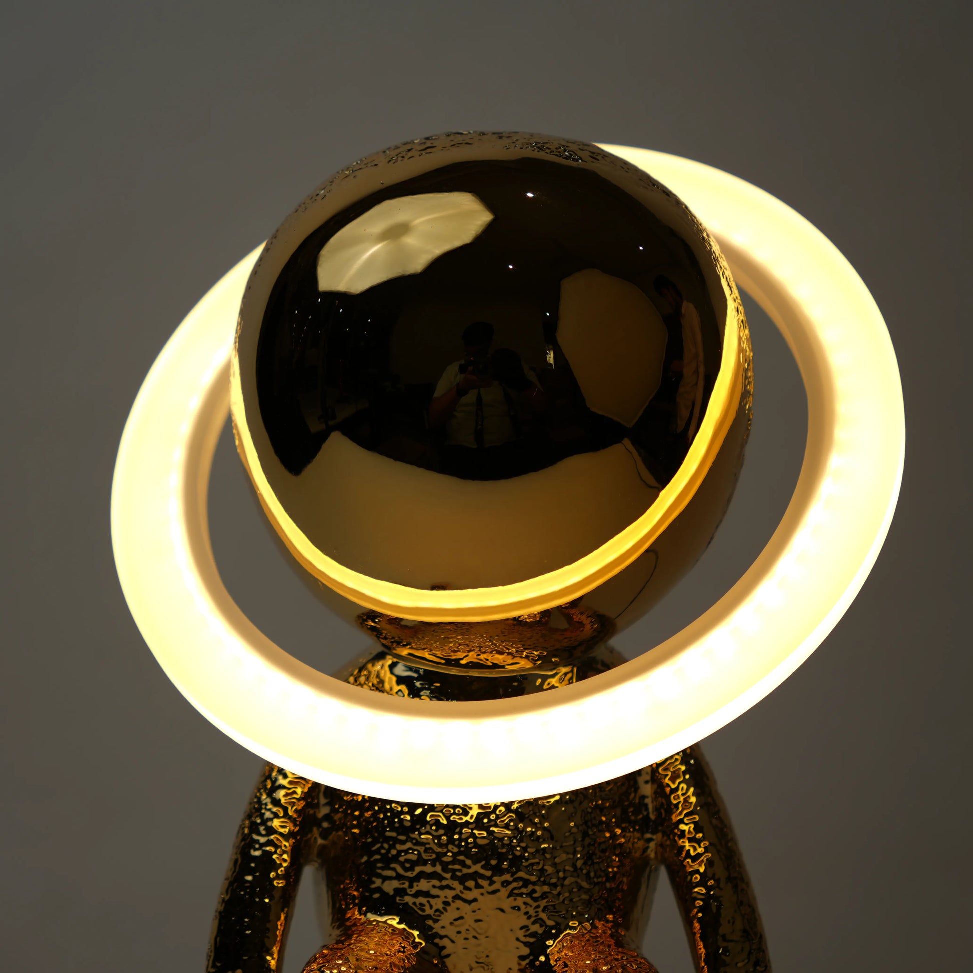 Gold and black spherical object with a glowing white ring on a dark background