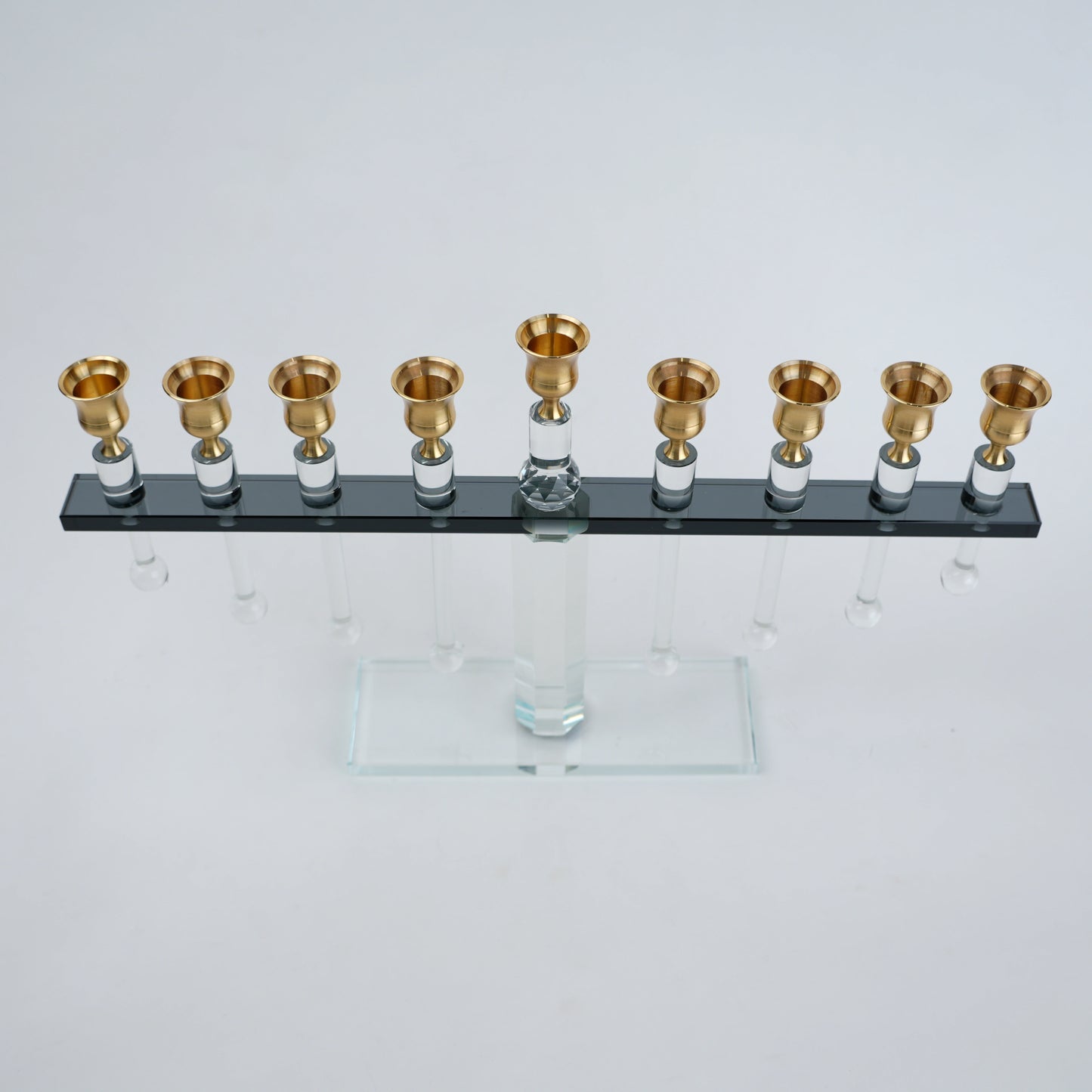 Menorah with gold candle holders on a clear base against a white background