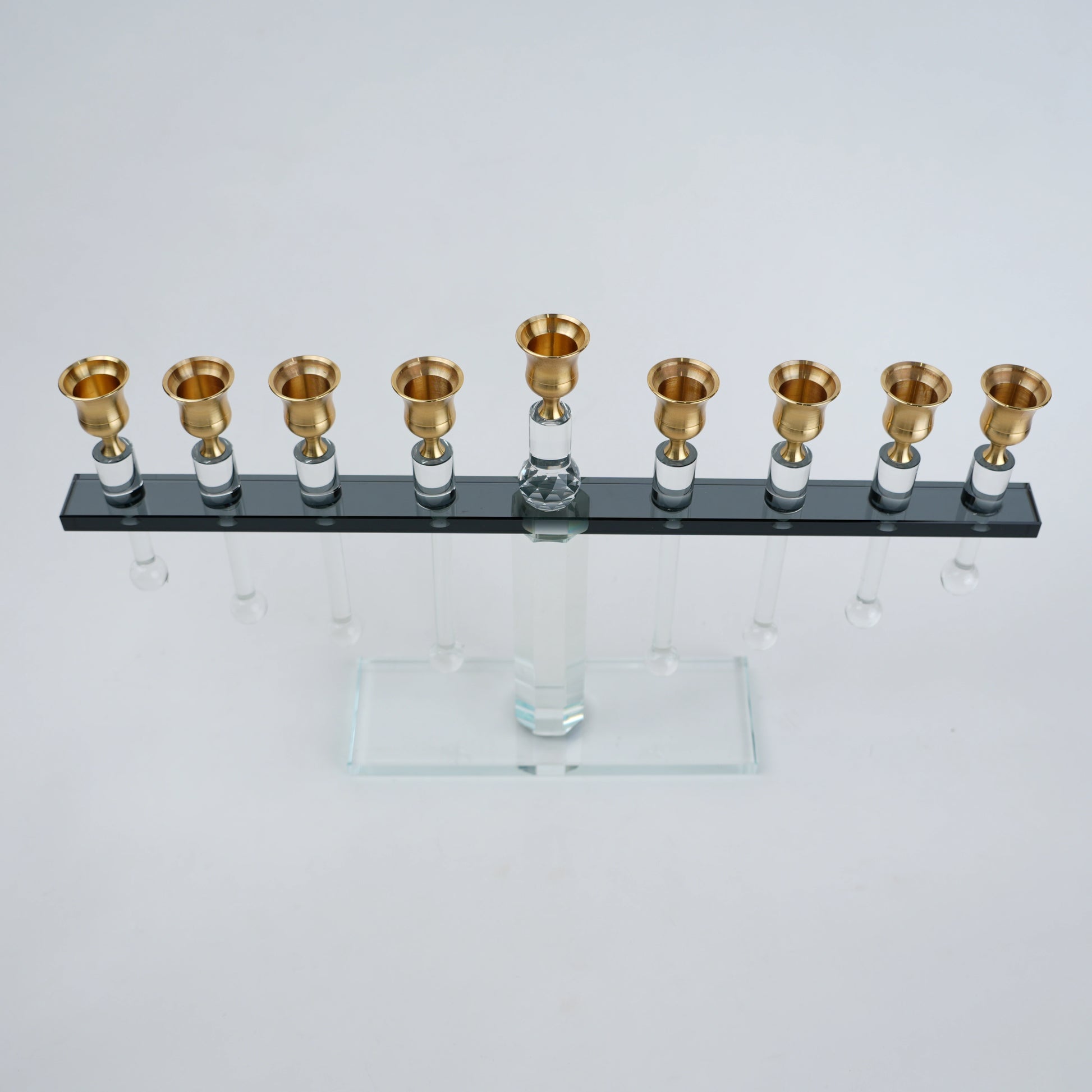 Menorah with gold candle holders on a clear base against a white background