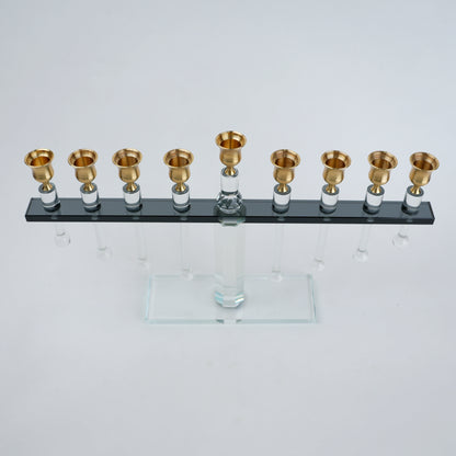 Menorah with gold candle holders on a clear base against a white background