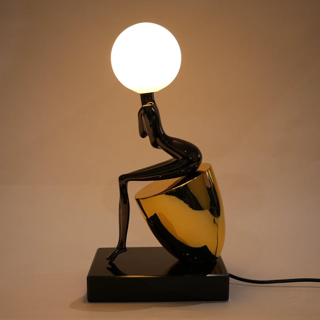 Black figure table lamp with glossy finish and spherical globe light mounted on a solid base