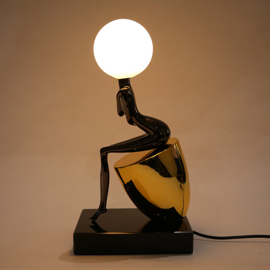 Black figure table lamp with glossy finish and spherical globe light mounted on a solid base