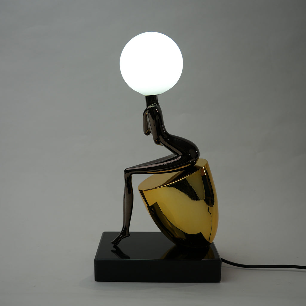 Black figure table lamp with glossy finish and spherical globe light mounted on a solid base
