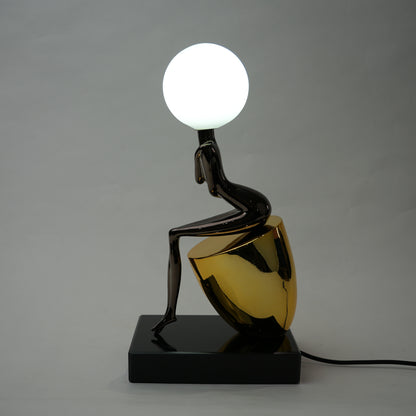 Black figure table lamp with glossy finish and spherical globe light mounted on a solid base