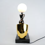 Black figure table lamp with glossy finish and spherical globe light mounted on a solid base