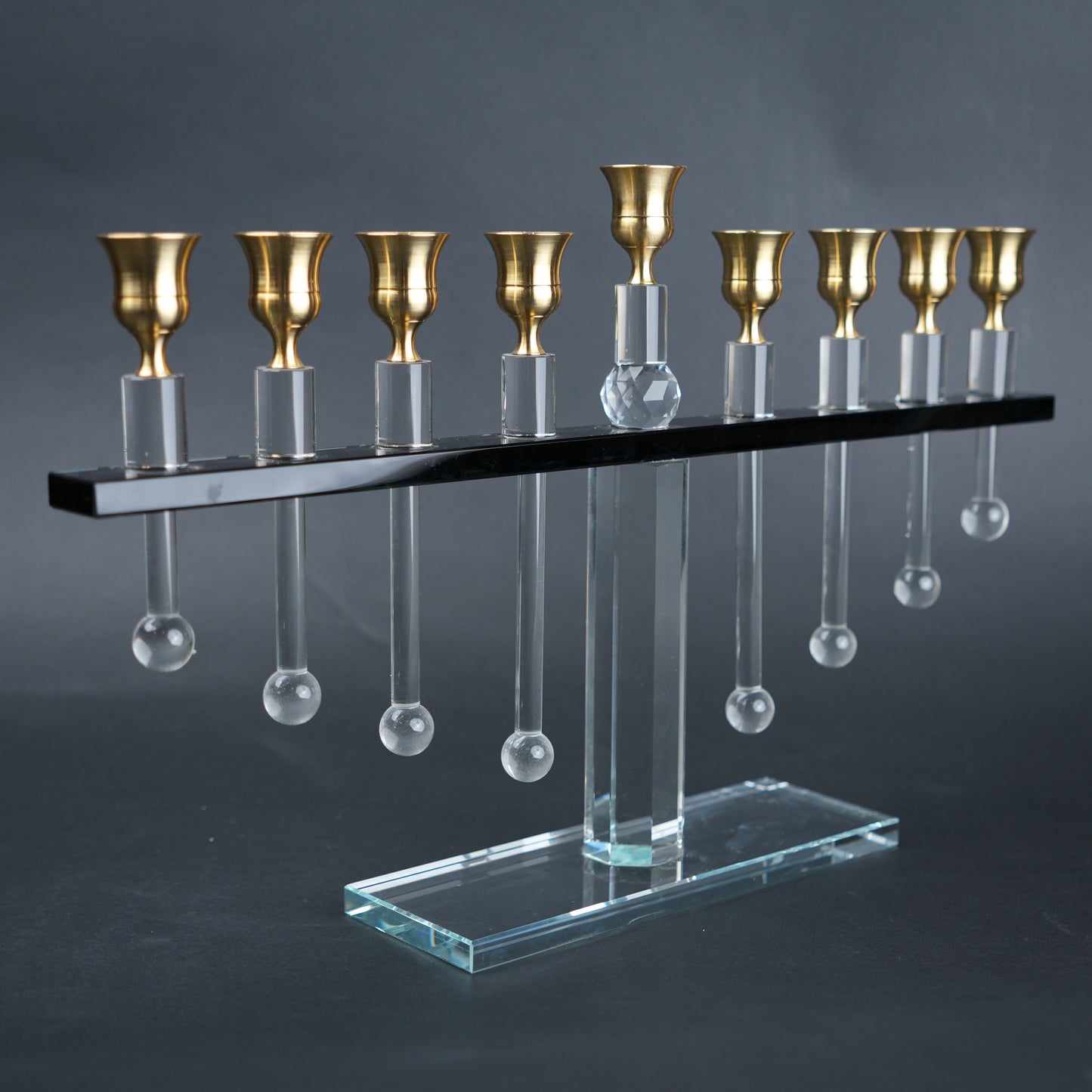 Decorative menorah with gold candle holders and clear glass droplets on a dark background