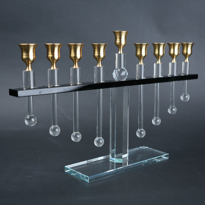 Decorative menorah with gold candle holders and clear glass droplets on a dark background