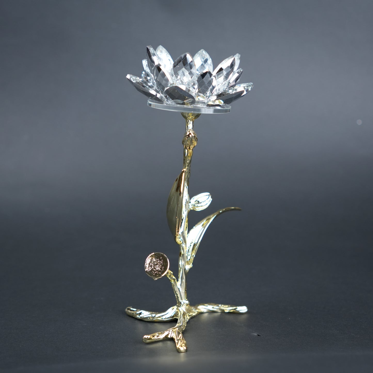 Decorative crystal object on a gold stand against a dark background