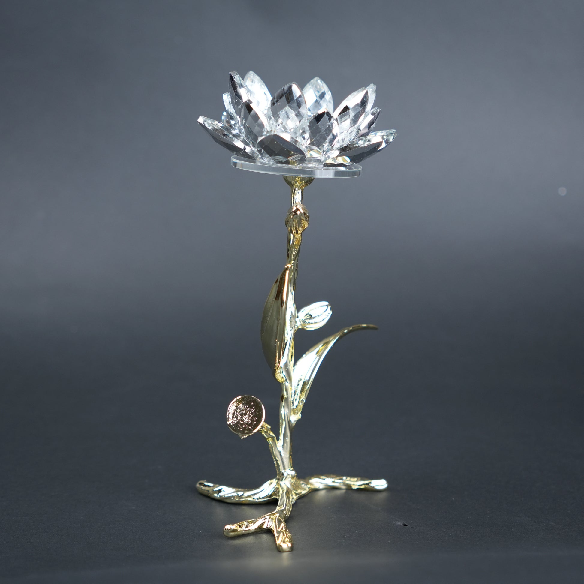 Decorative crystal object on a gold stand against a dark background