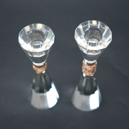 Two crystal candle holders with bronze bases on a dark background