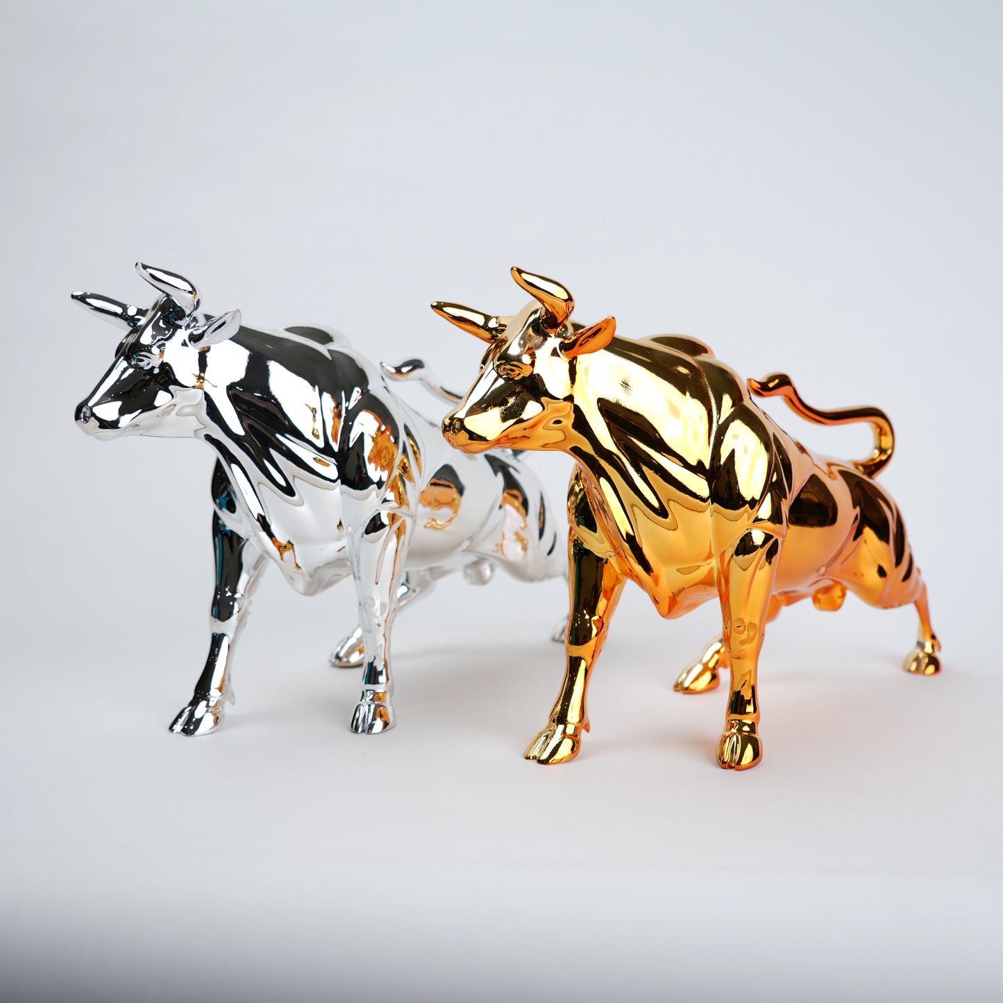 Gold and silver bull figurines on a light gray background