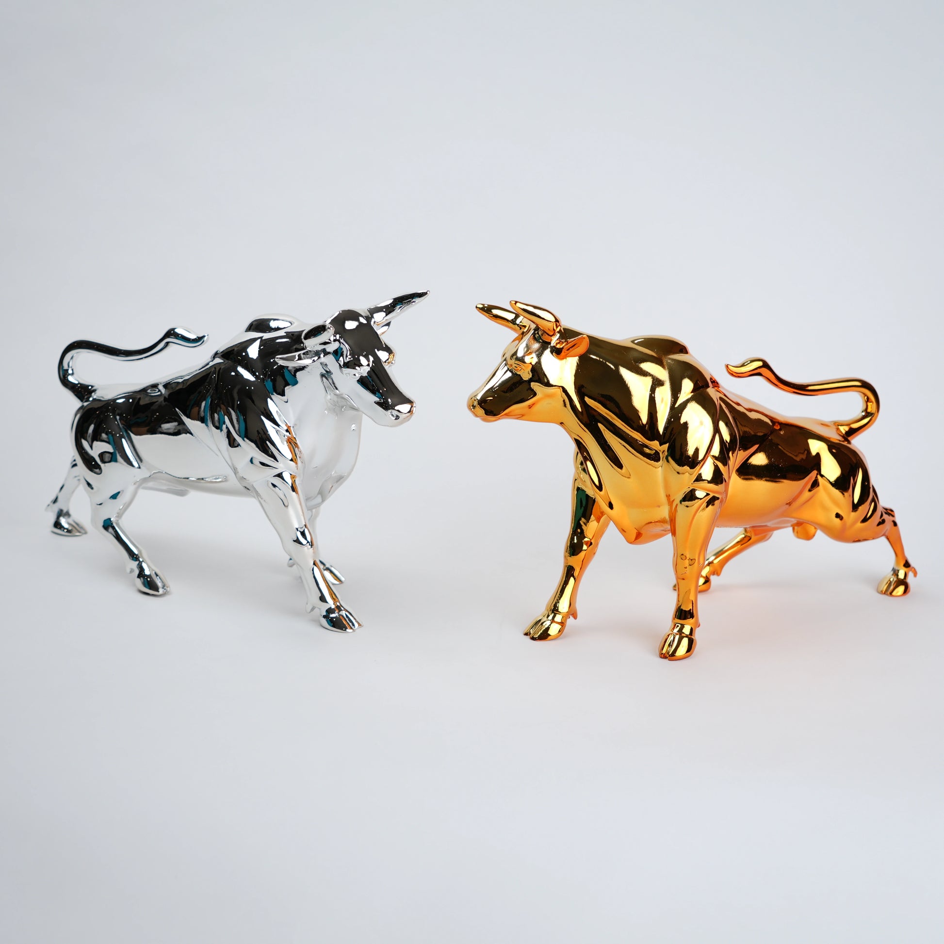 Gold and silver bull figurines on a light gray background