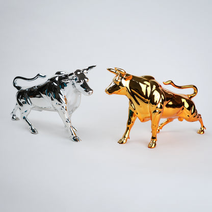 Gold and silver bull figurines on a light gray background