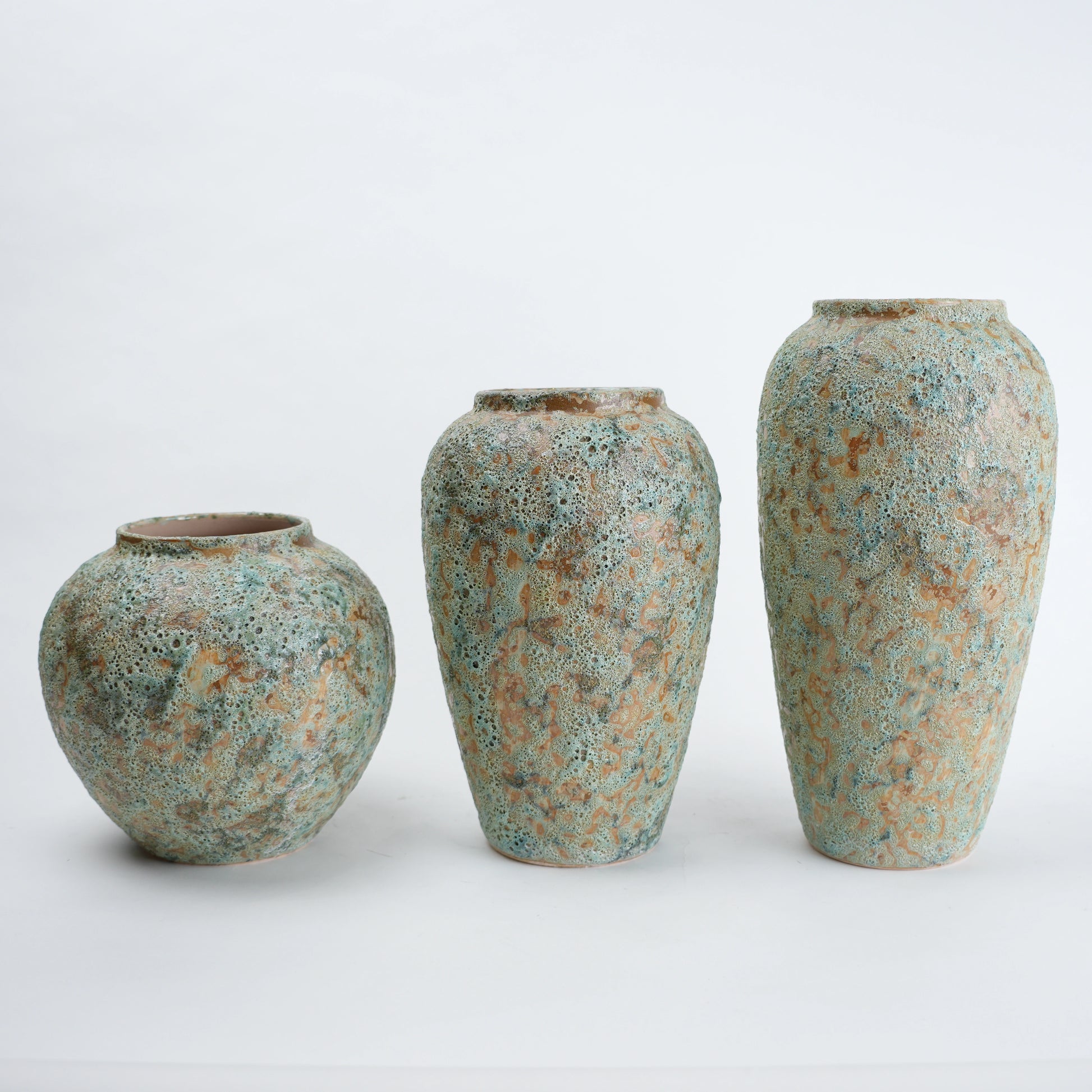Three ceramic vases with textured surfaces on a white background