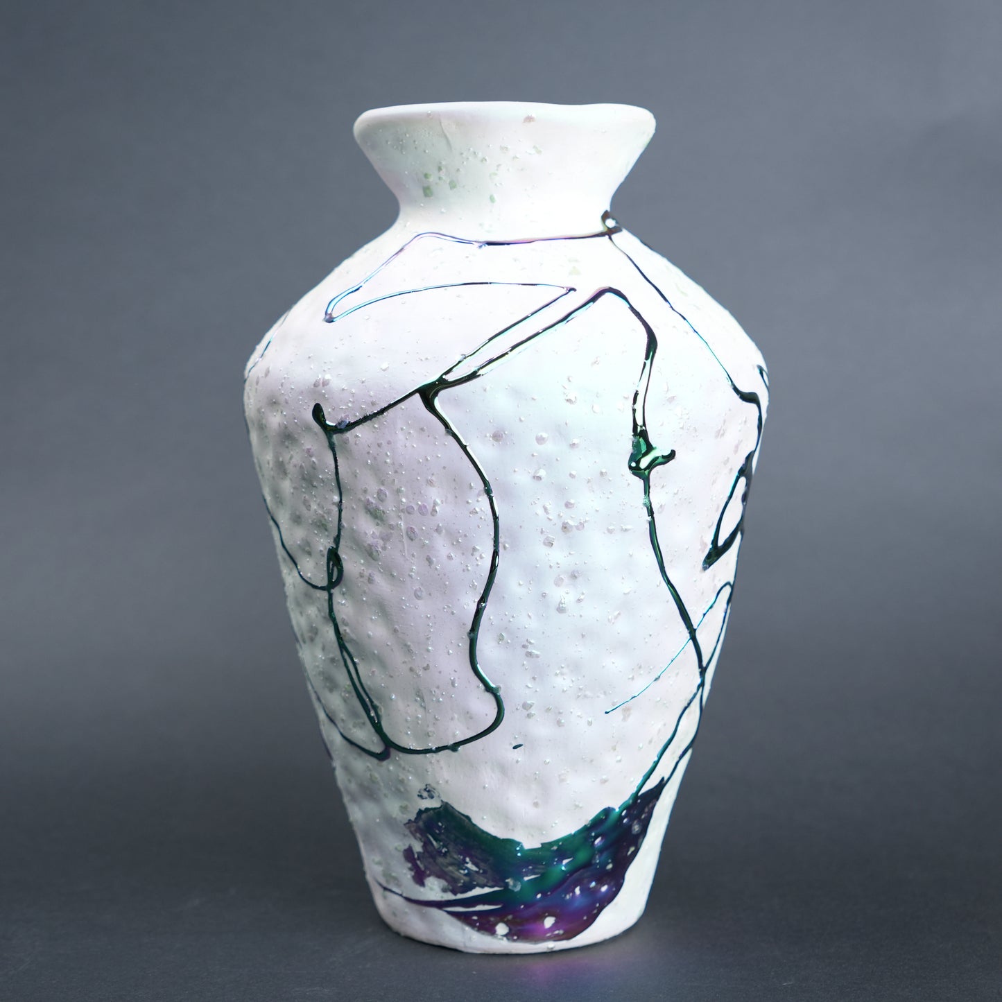 White ceramic vase with abstract black and blue line art on a gray background