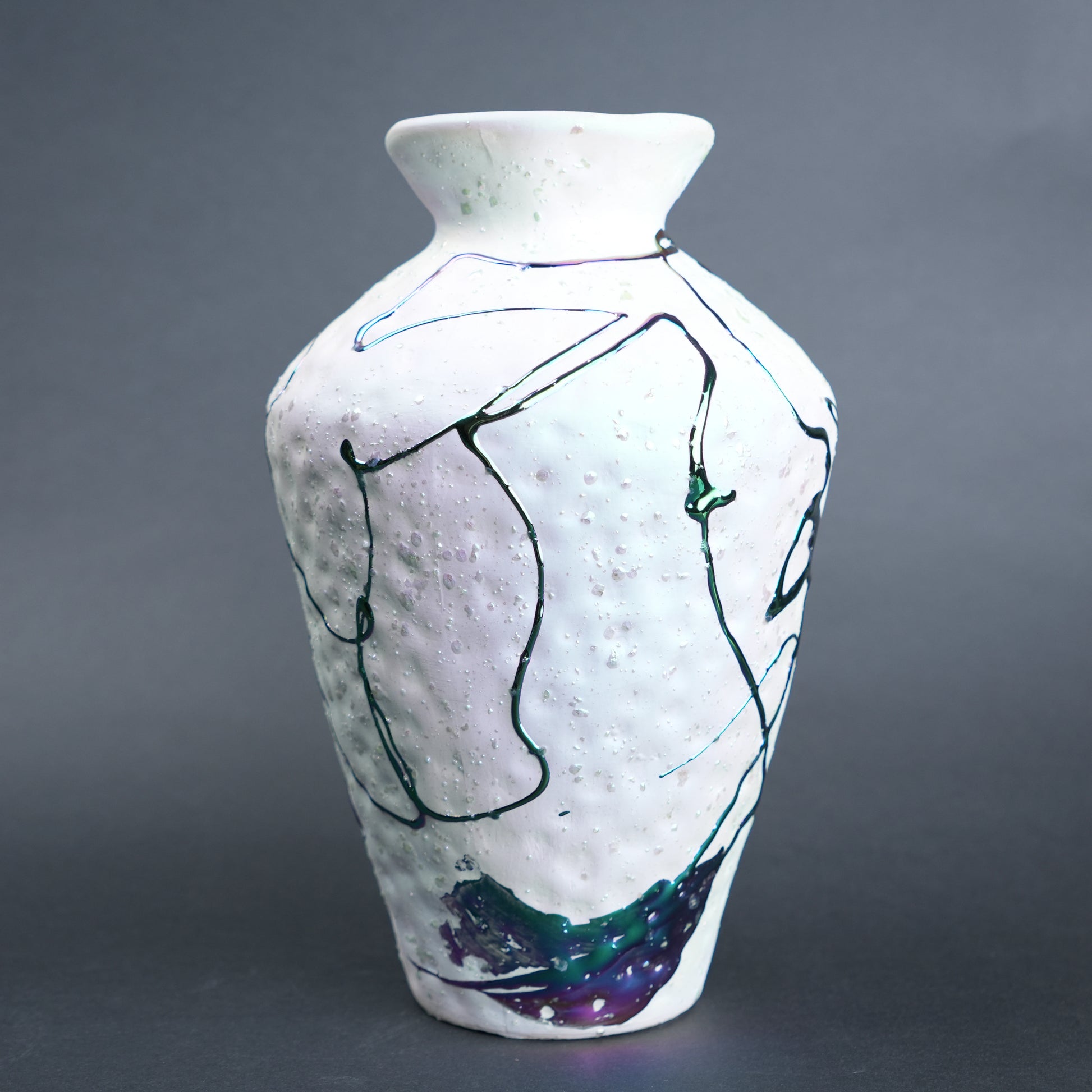 White ceramic vase with abstract black and blue line art on a gray background
