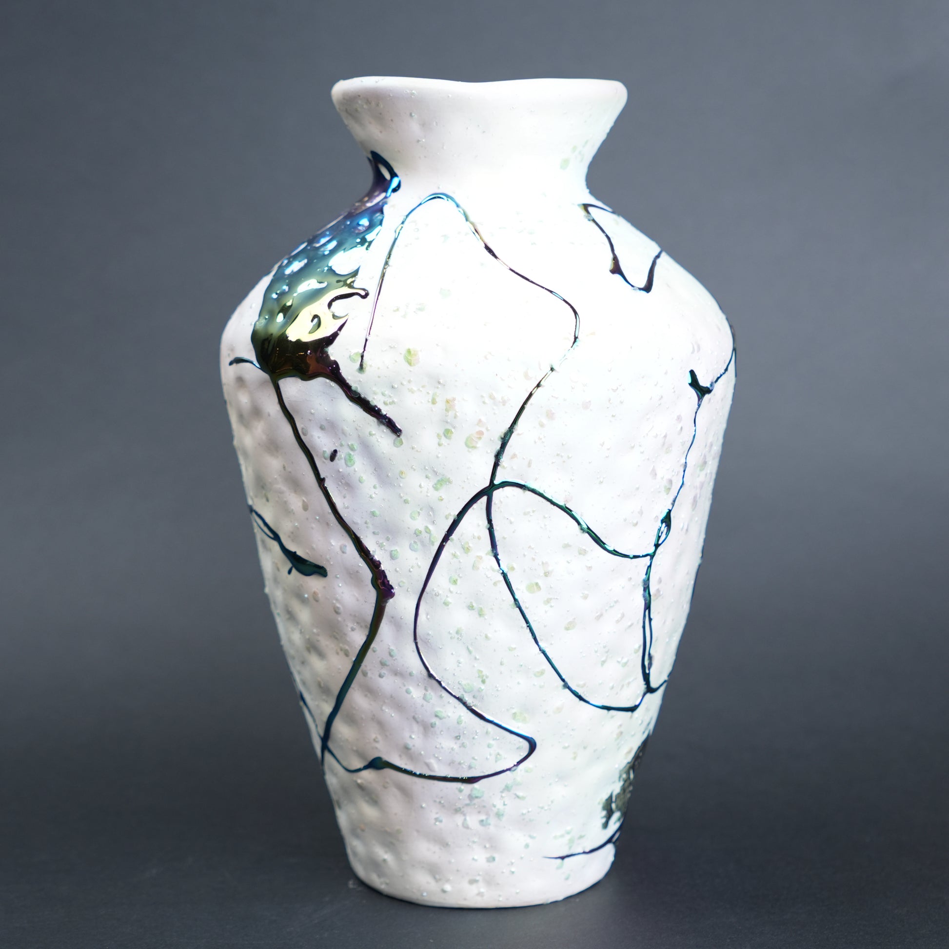 White ceramic vase with abstract black and blue designs on a gray background