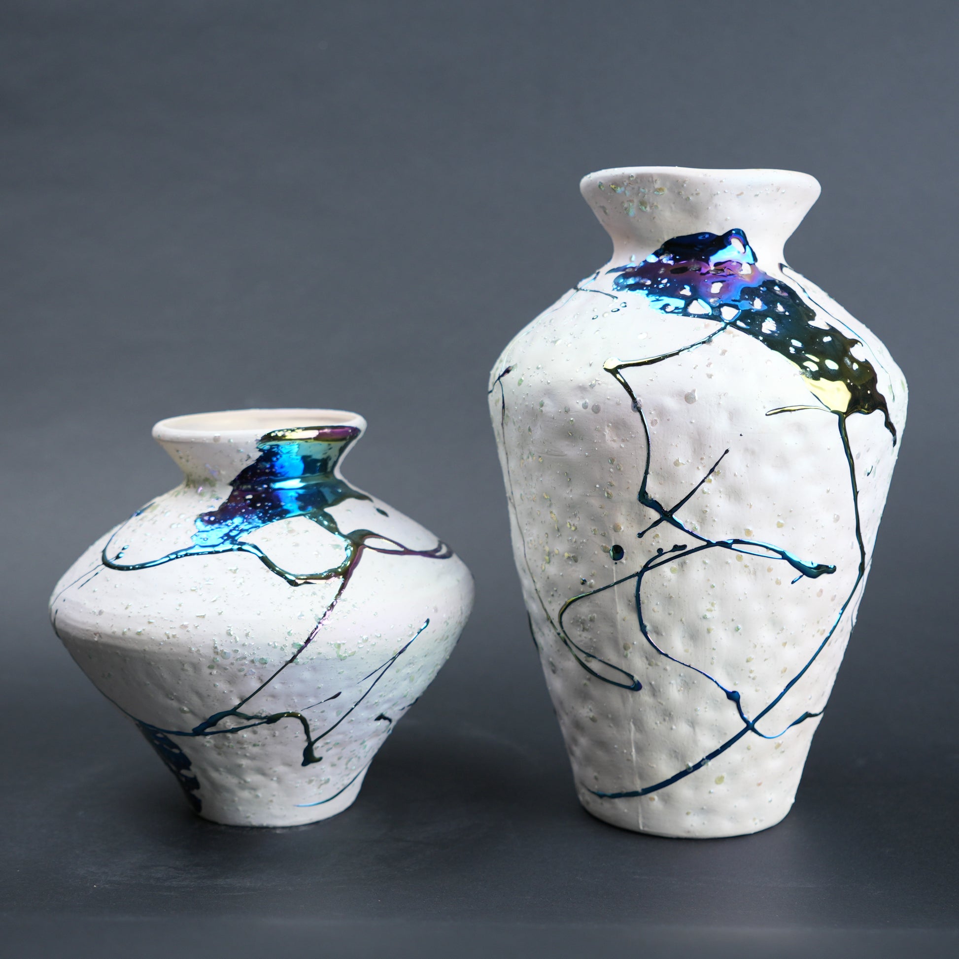 Two ceramic vases with abstract designs on a gray background