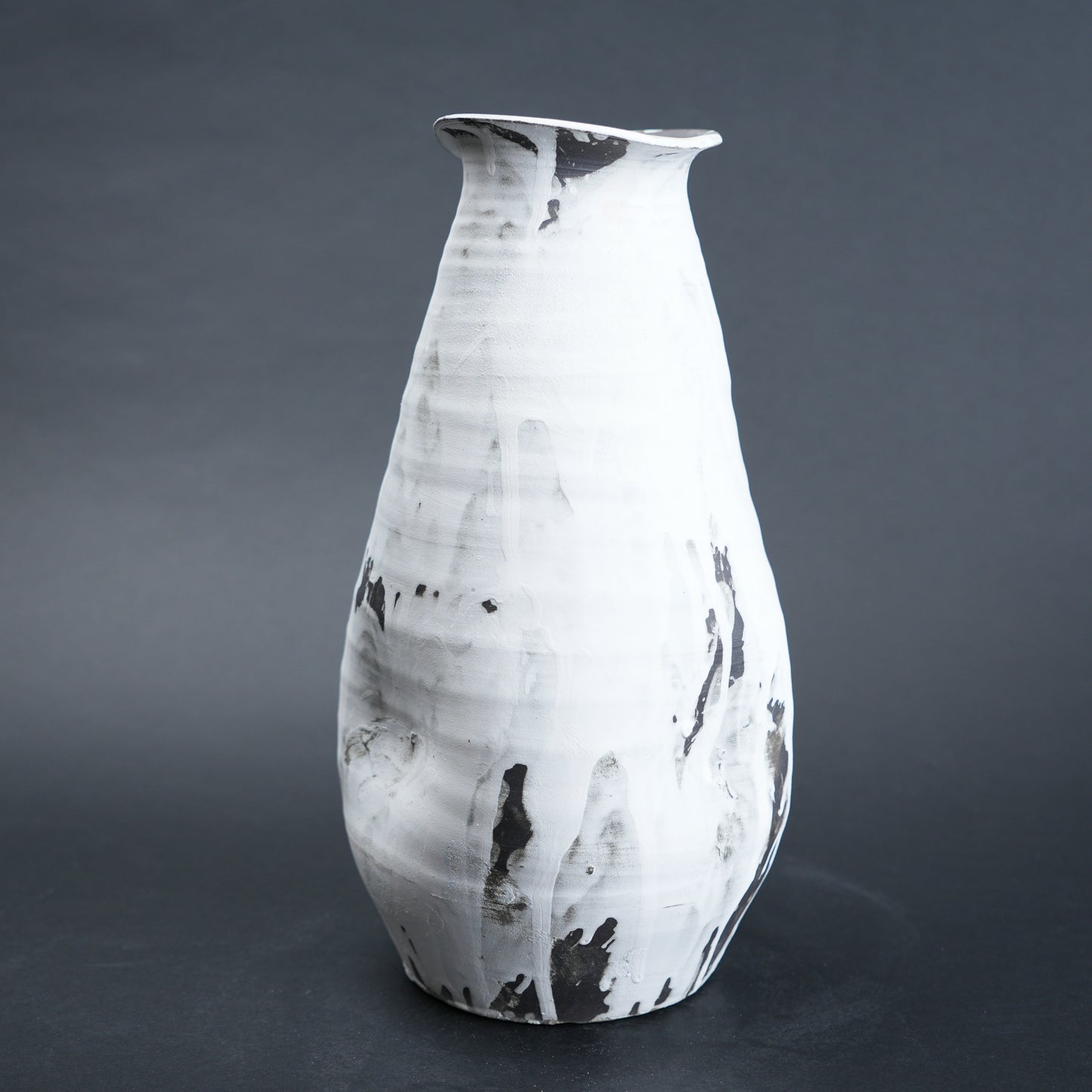 White ceramic vase with black marbled patterns on a dark gray background