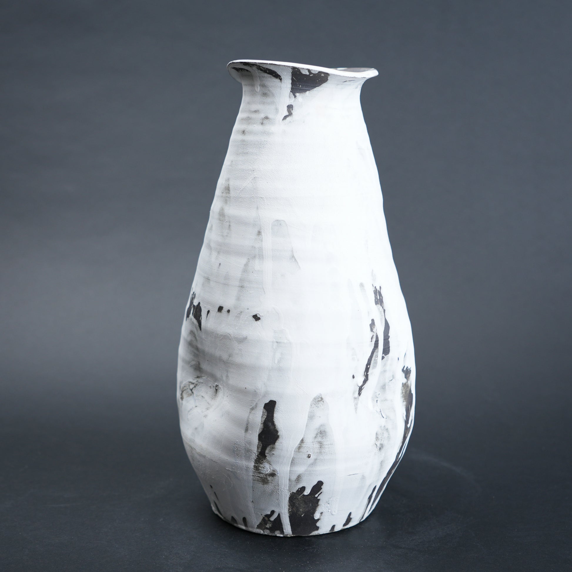 White ceramic vase with black marbled patterns on a dark gray background
