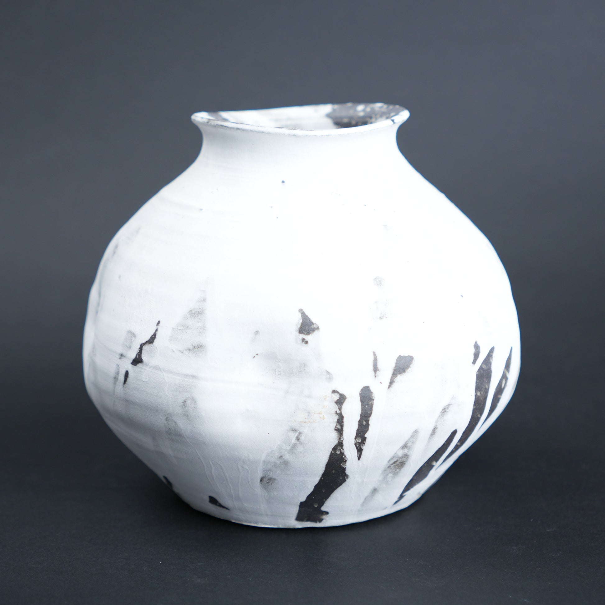 White ceramic vase with black abstract patterns on a dark gray background