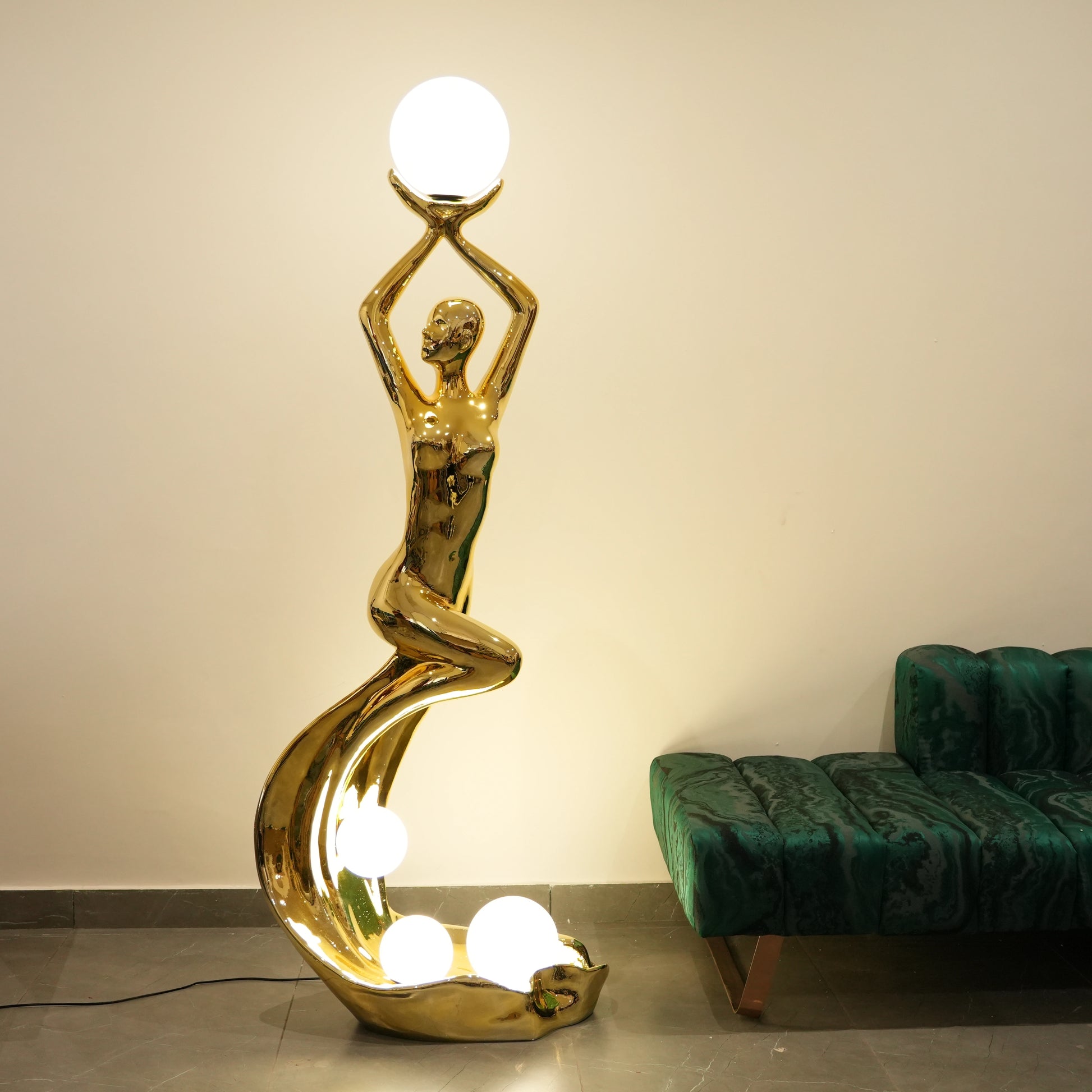 Gold floor lamp shaped like a dancer with a green sofa in the background