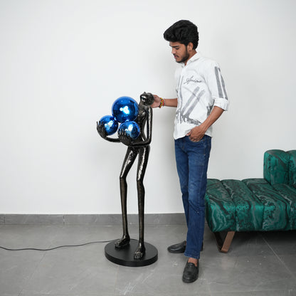 Man standing next to a unique black and blue sculpture in a room with a green couch.