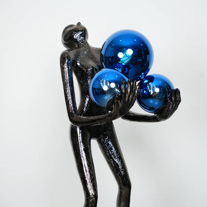 Black figurine holding three blue spherical objects against a white background